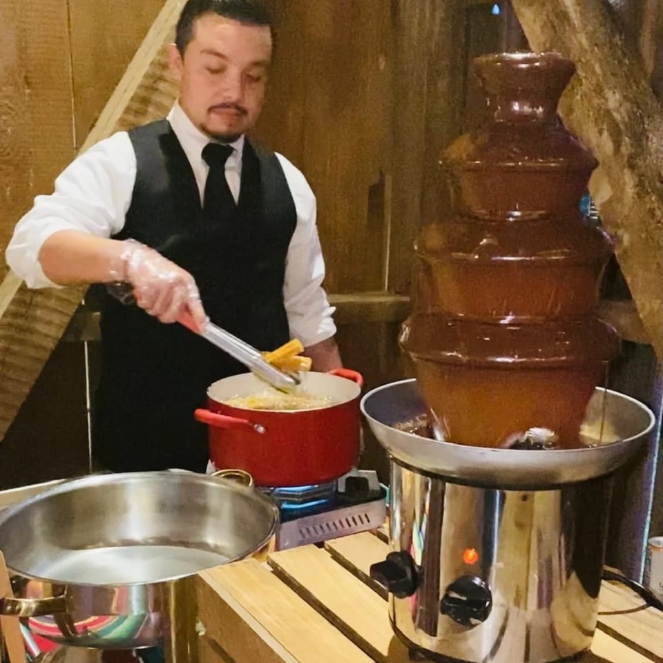 A server prepares churros next to a flowing chocolate fountain at Cielito Lindo Mexican Food.