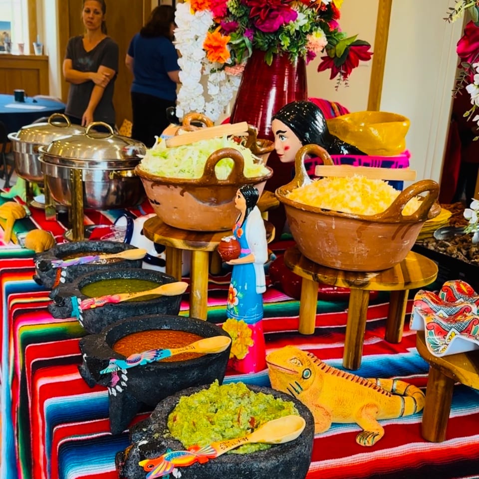 A vibrant Mexican buffet with molcajetes of salsa and guacamole, and large bowls of rice and cabbage.